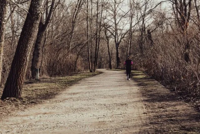 Alergător pe o alee presărată cu frunze căzute, într-un parc dimineața